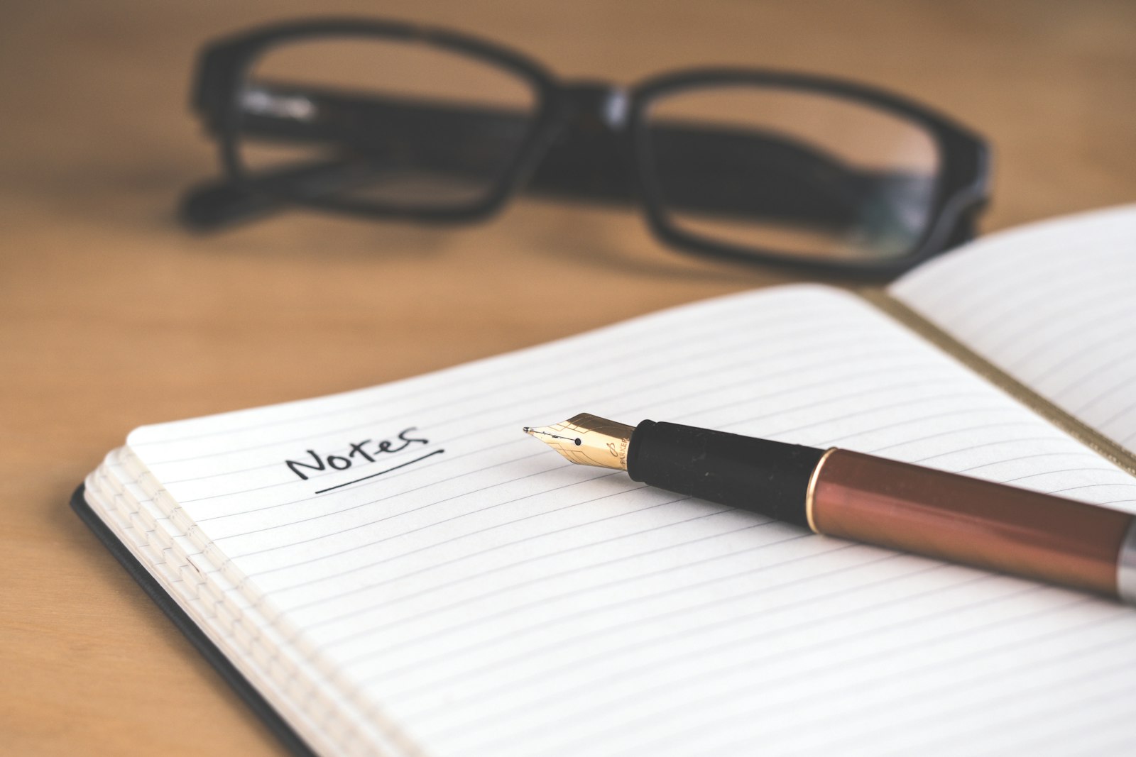 An open notebook labeled Notes beside a pen and glasses